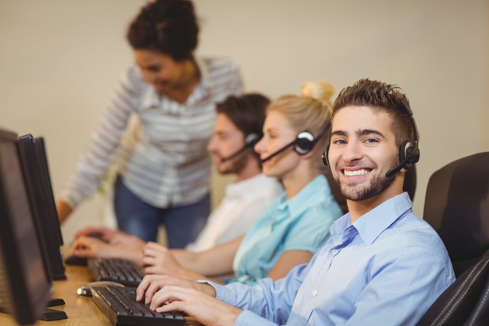 Portrait of male employee with coworkers working in call center